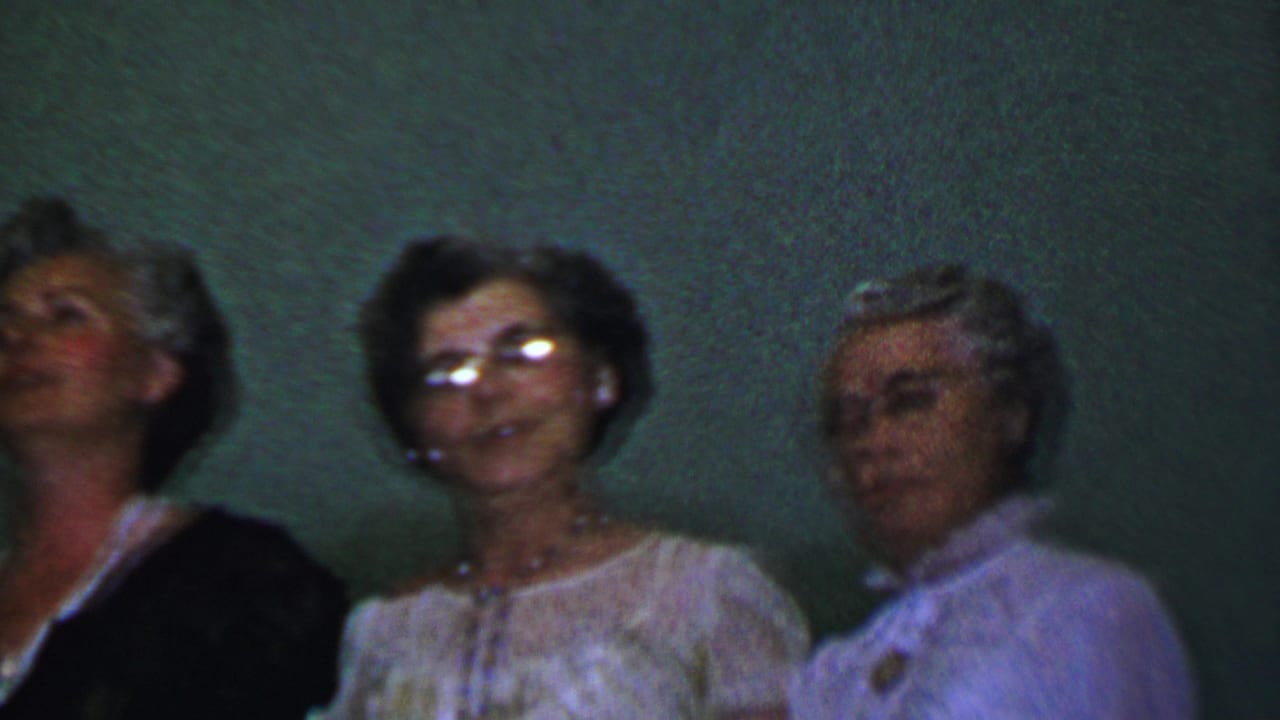 Close grouping of adult women singing, including one woman leaning toward another.