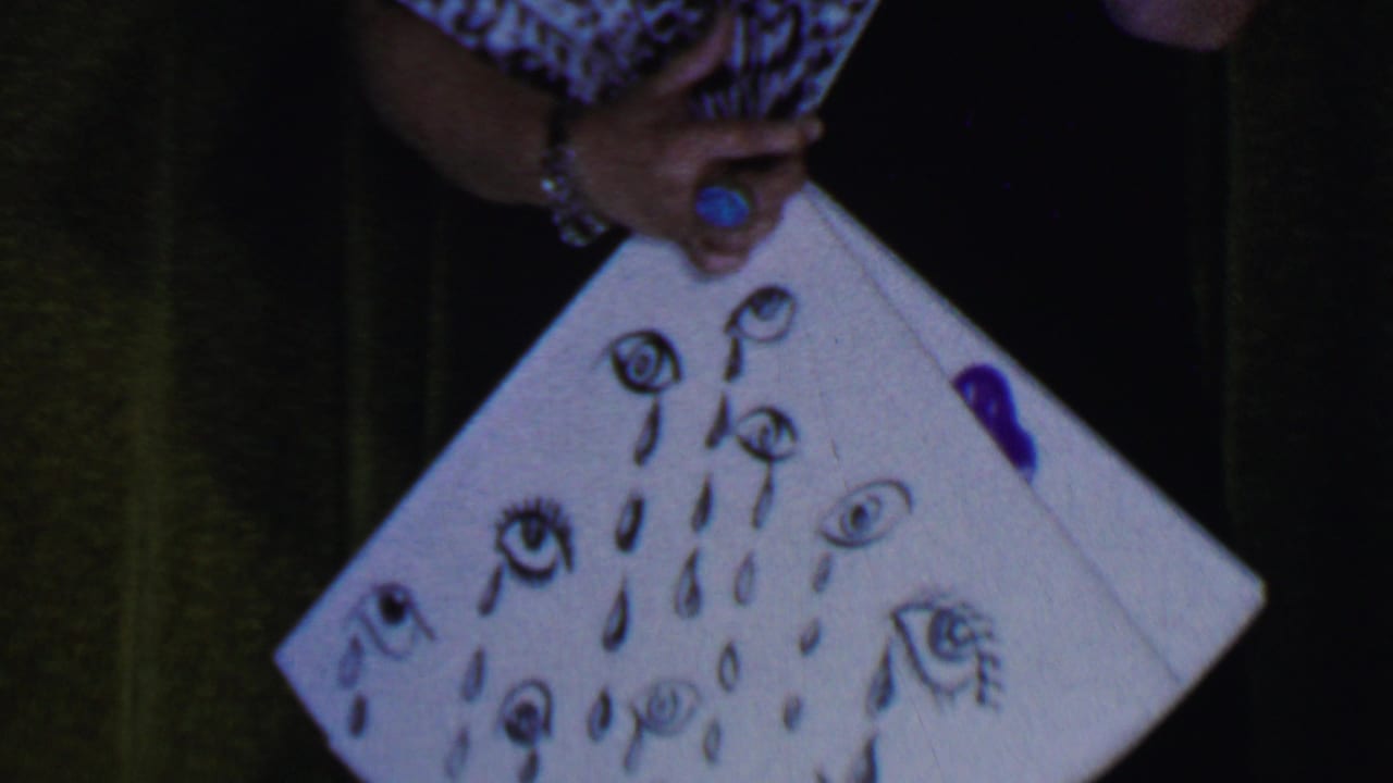 Woman in a pink hat leans over a board decorated with crying eyes.