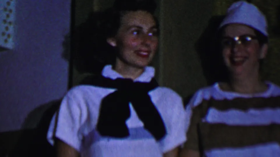 Women in supported 1956 Dallas home-movie footage smile and laugh indoors, including one in a sailor-style top and others in striped tops and hats.