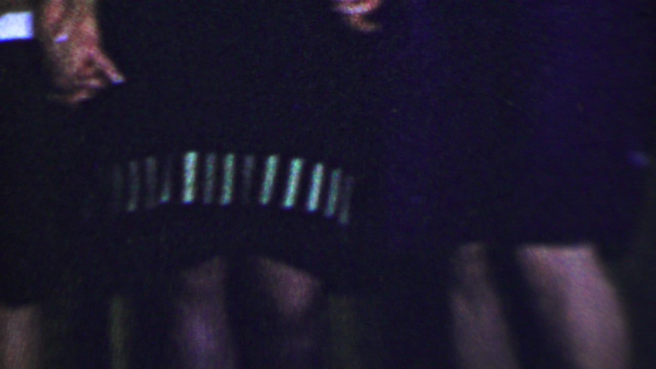 Close cropped view of women in dark and striped clothing, with faces partly cut off by the frame.
