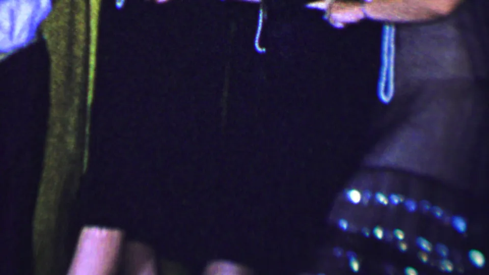 Three women in Dallas, Texas, 1956 footage stand together smiling in formal dresses, with clasped or overlapping hands visible against a gold curtain setting.
