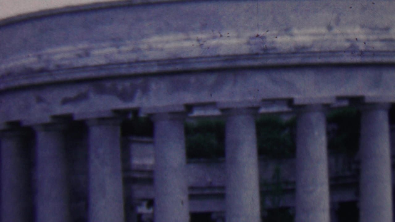 Closer angled view of the curved entablature and row of stone columns.