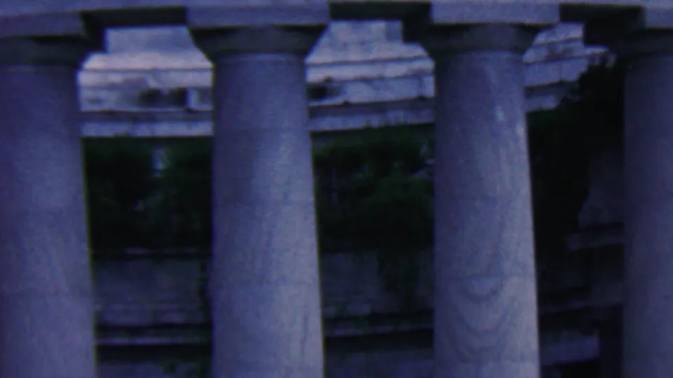 1961 8mm view of the monument's column bases, recessed dark portico spaces, stone trim, and greenery in Covington, Kentucky.