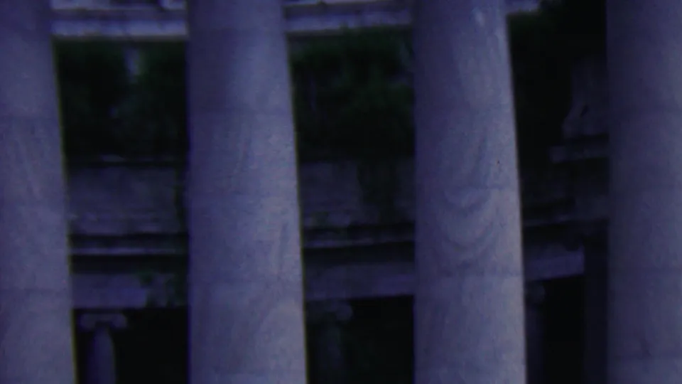 Covington, Kentucky 1961 home-movie frame showing tall classical stone columns and shadowed monument architecture in soft 8mm focus.