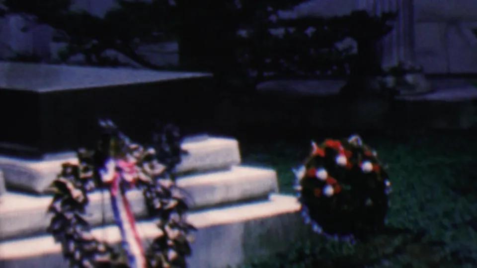 Covington, Kentucky 1961 home-movie frame showing wreaths, ribbons, stone steps, and column bases in a subdued monument setting.