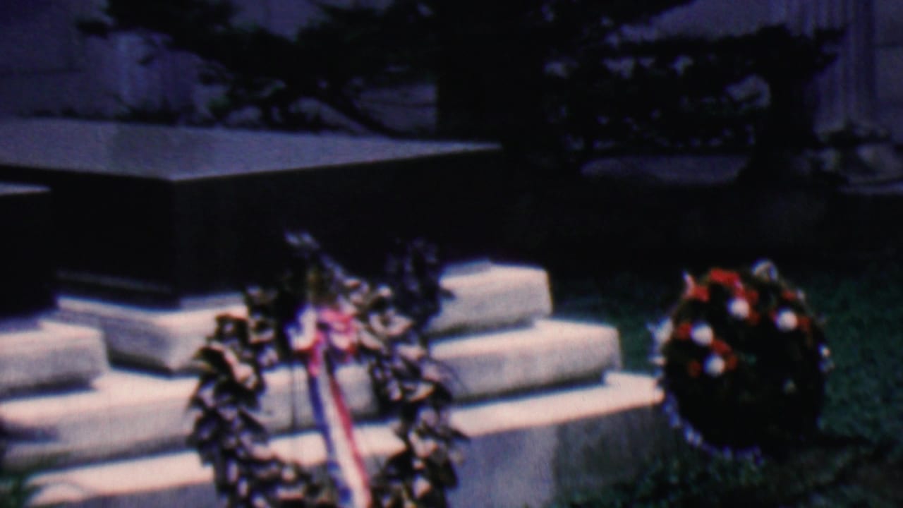 Covington, Kentucky, 1961 home-movie frame showing floral wreaths with a ribbon beside stone steps at an outdoor memorial site.