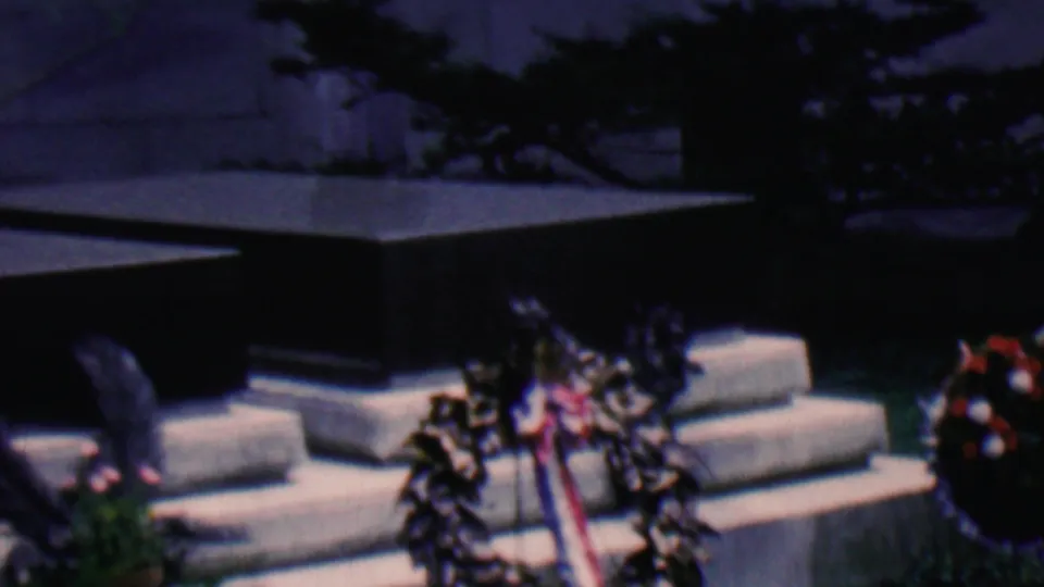 Covington, Kentucky, 1961 8mm frame showing memorial wreaths, a striped ribbon, grass, and pale stone steps under uneven exposure.