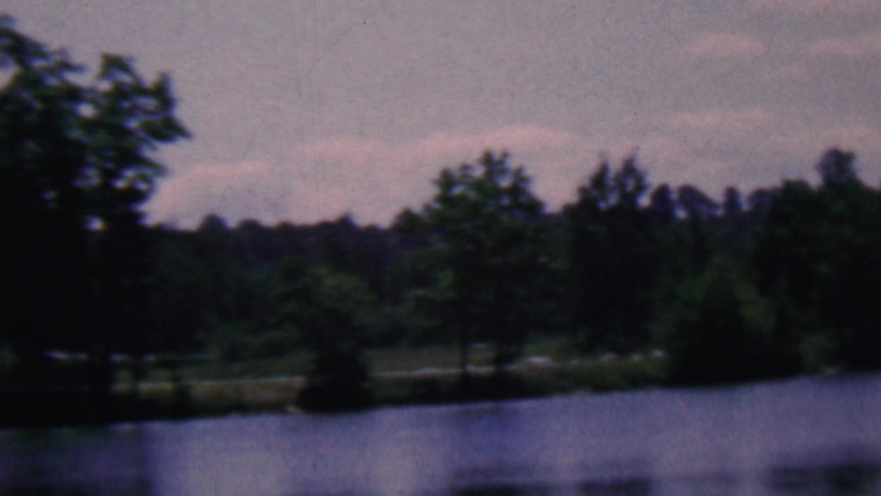 Trees and distant shoreline seen across a dark lake surface.