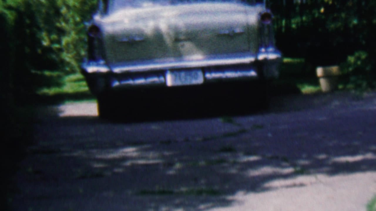Rear view of a light-colored mid-century American car parked on a leafy driveway in Hatfield, Pennsylvania, in 1956 home-movie footage.