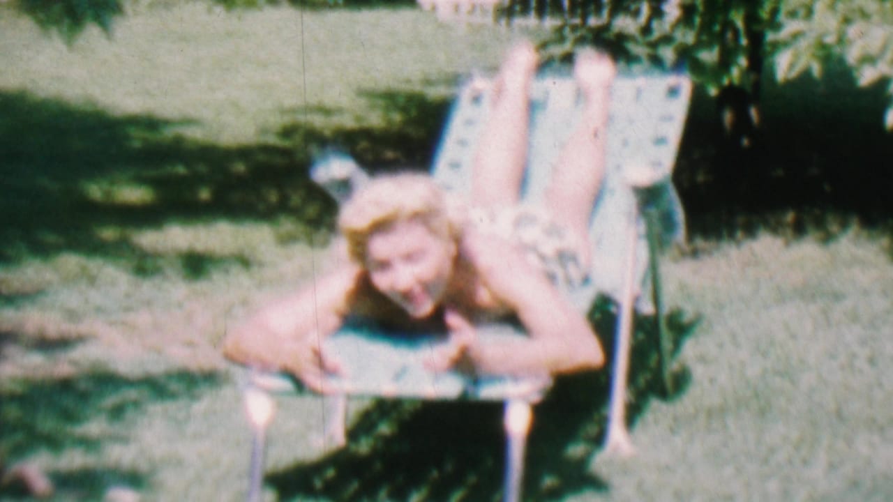 Young woman sunbathing on a metal lawn chair in a grassy backyard.