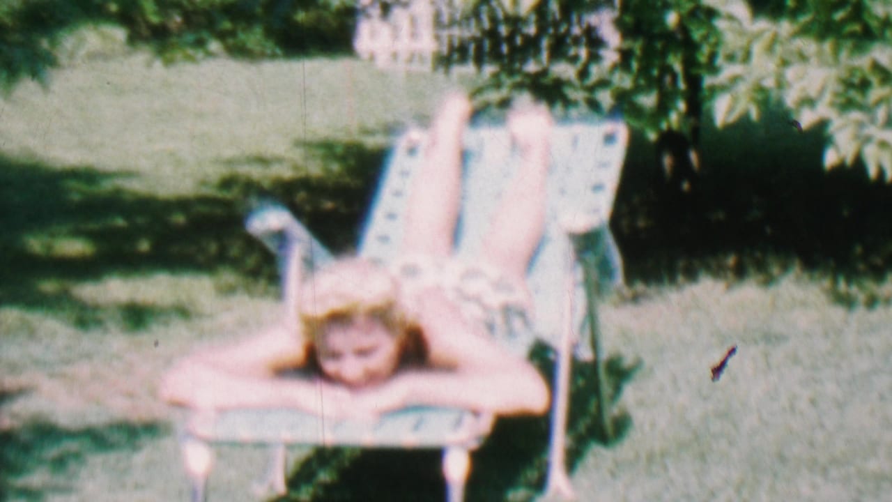Young woman lies face-forward on a lawn chair with her legs raised.