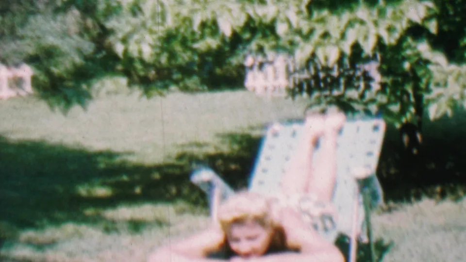The closing frame keeps the young woman on the metal lawn chair in the Hatfield backyard, surrounded by grass, foliage, and dappled summer light.