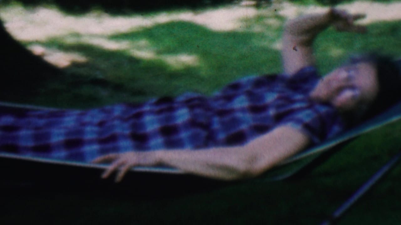 1956 Hatfield, Pennsylvania frame showing the woman stretched out in the hammock, her plaid shirt visible against the shaded lawn.