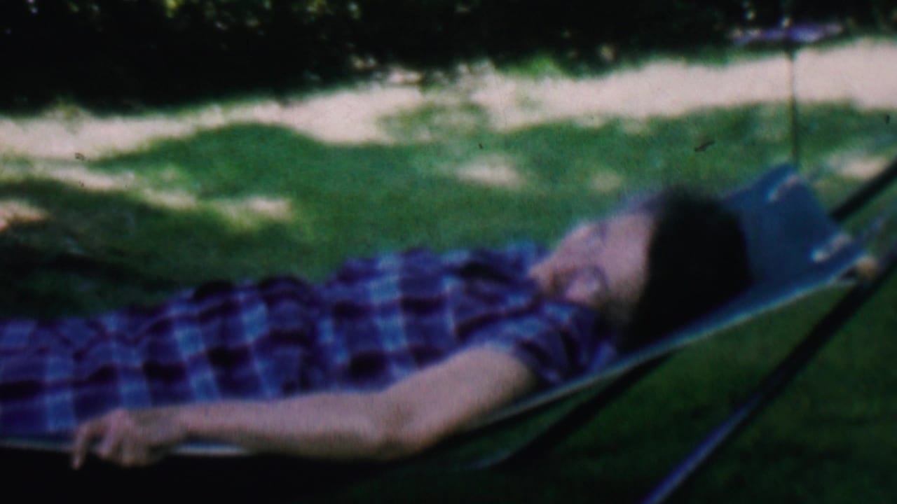 Older man lies back in a hammock with his head turned upward.