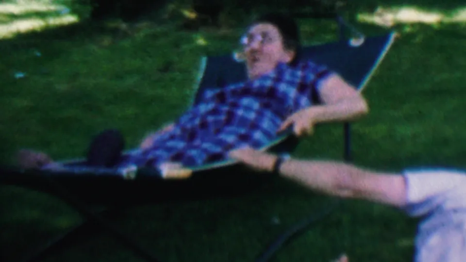 The older man sits back in the lawn hammock with one leg extended, framed by green grass and shade in this Hatfield, Pennsylvania 8mm home-movie still.