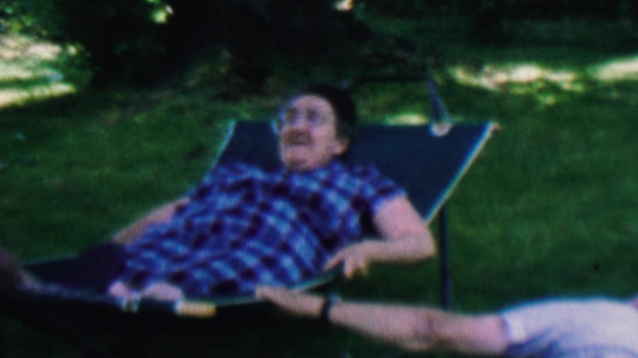 Smiling man reclines in a lawn chair while another person lies nearby.