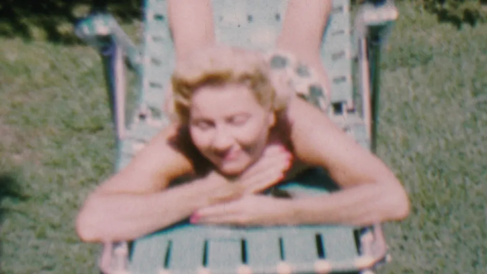 In a later frame from the Hatfield, Pennsylvania clip, the woman lies face down on a green lawn chair, smiling toward the camera in bright outdoor light.