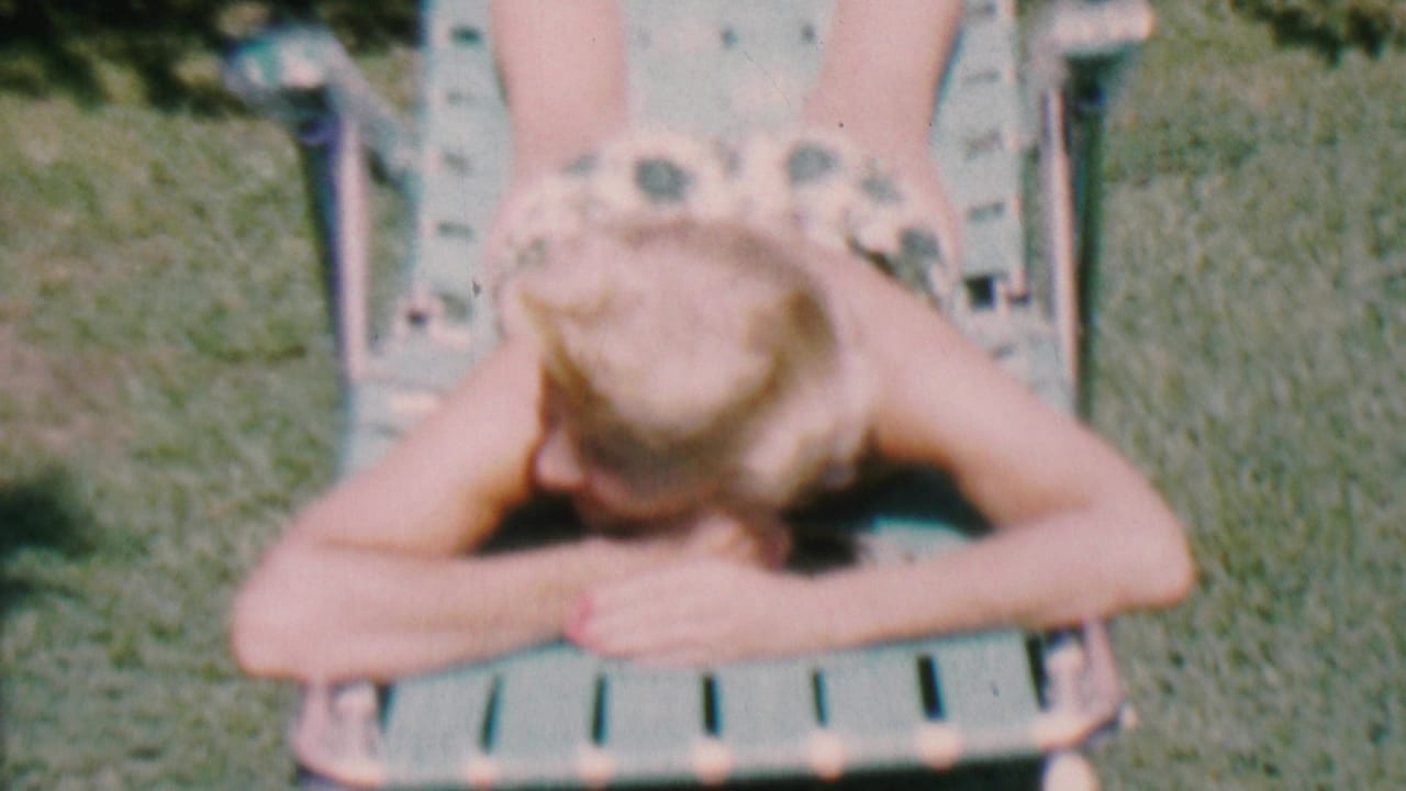Adult woman lies face down on a green lawn chair in grass with her head turned downward.