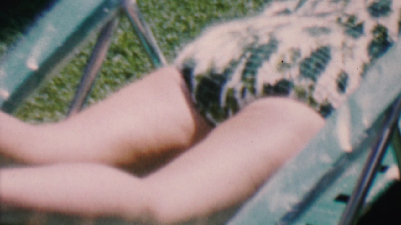 Close view of a person reclining in a patterned swimsuit beside lawn chair tubing.