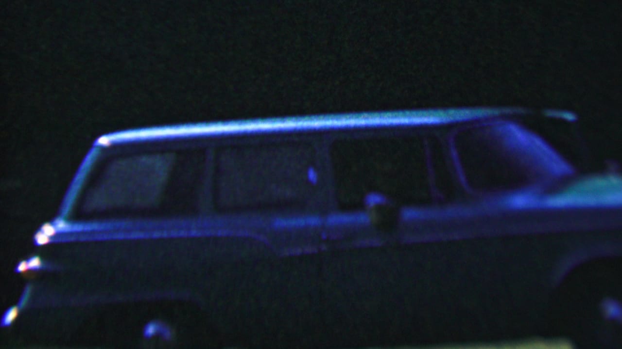 A blue-tinted 1950s station wagon appears in profile at night in Hatfield, Pennsylvania, with windows and trim faintly visible through heavy 8mm grain.