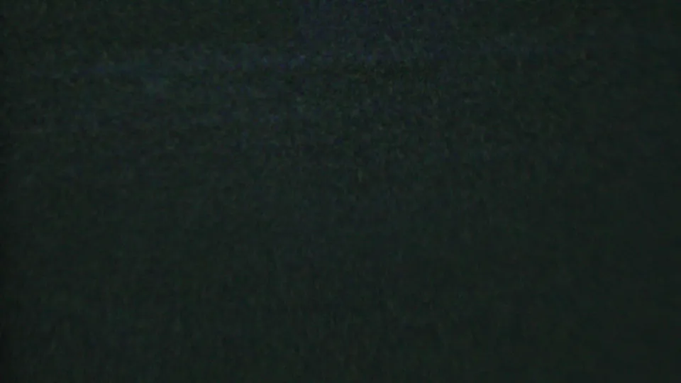 A dark, grainy 8mm frame shows little identifiable subject detail beyond low-light texture and the contact-sheet boundary from the extracted stills.