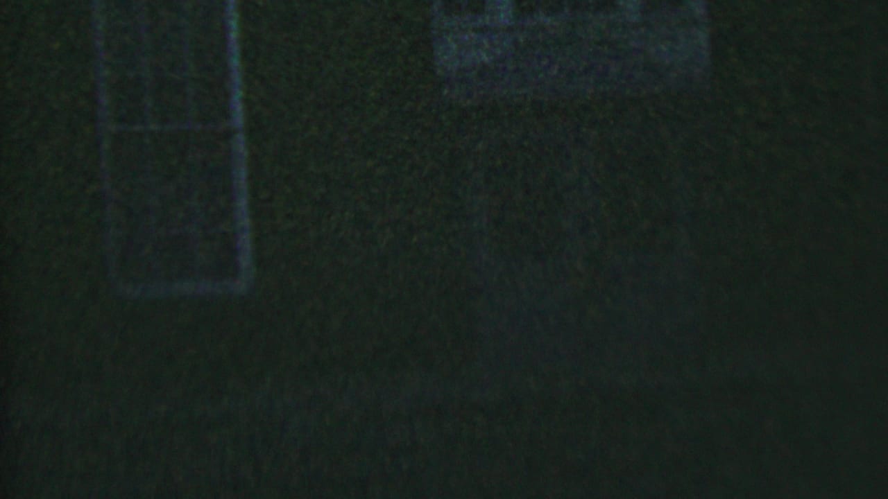 Dark brick wall with narrow windows in heavy nighttime grain.