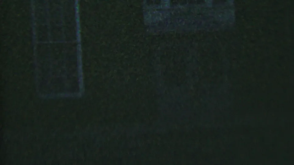 1956 Hatfield, Pennsylvania home-movie frame showing a dark brick house exterior with narrow windows barely visible in low light.
