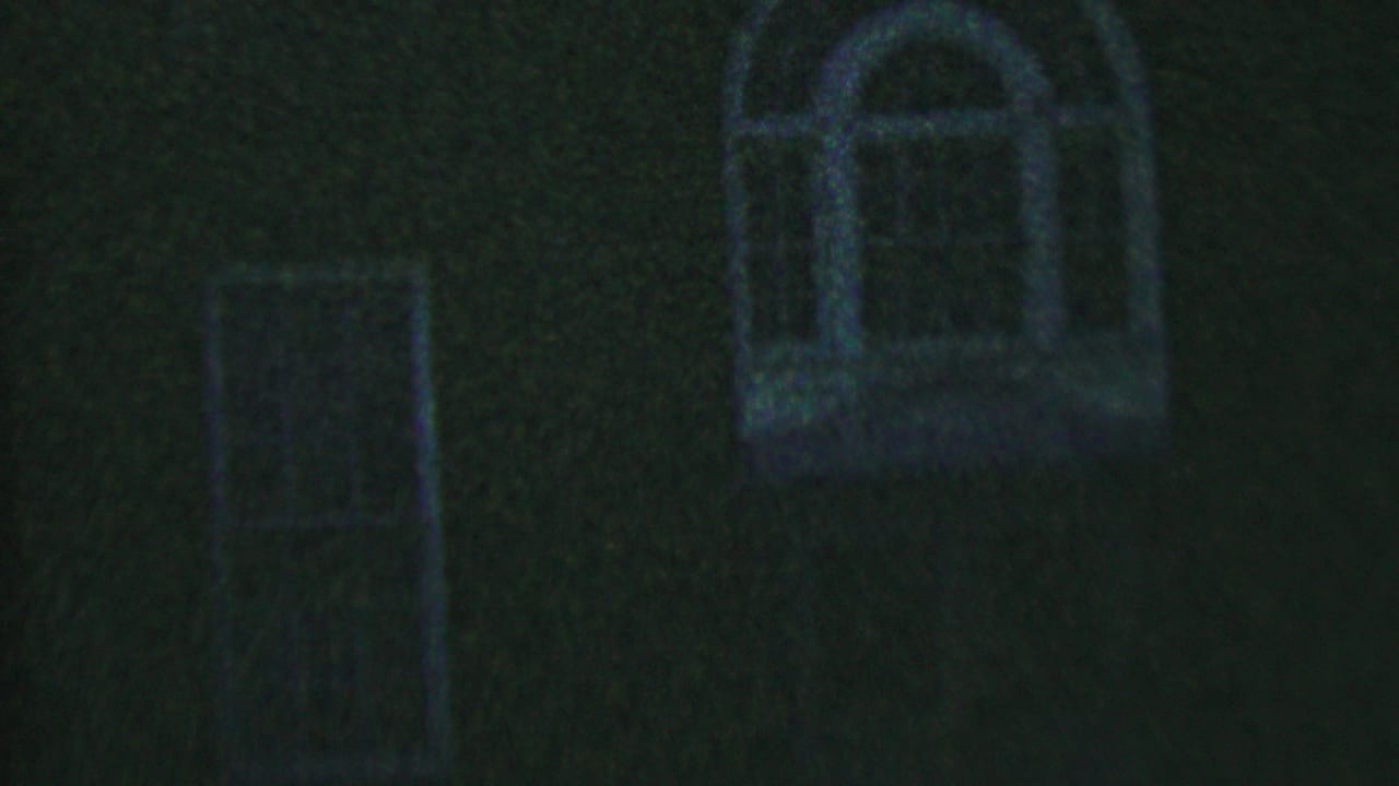 Dim brick exterior with a narrow window and arched window at night.