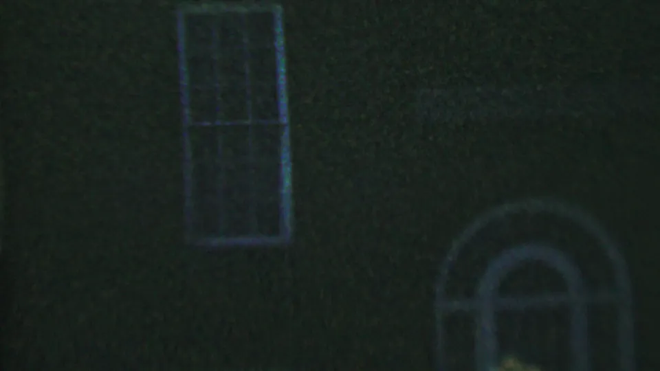 1956 Hatfield, Pennsylvania 8mm frame showing a dim dark facade with a tall multi-pane rectangular window and pale arched architectural trim below.