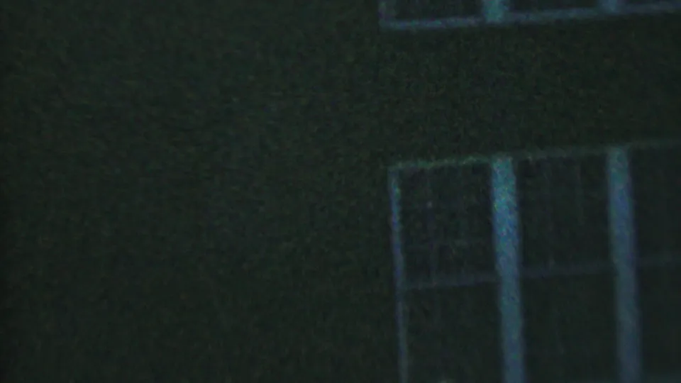1956 Hatfield, Pennsylvania 8mm frame showing lower white-framed windows on a dark residential exterior, with heavy grain and soft focus.