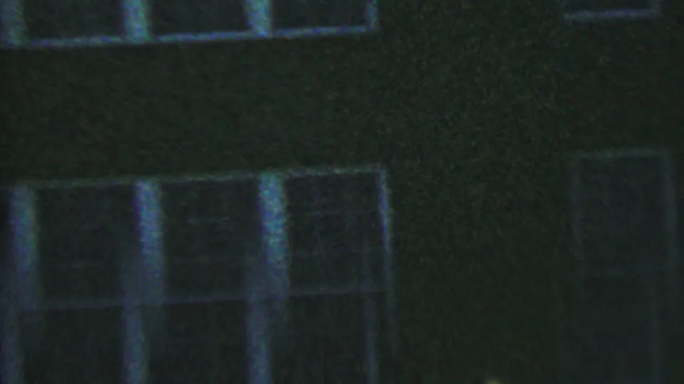 1956 Hatfield, Pennsylvania 8mm frame of a shadowed house facade with white-framed windows, low exposure, and visible film grain.