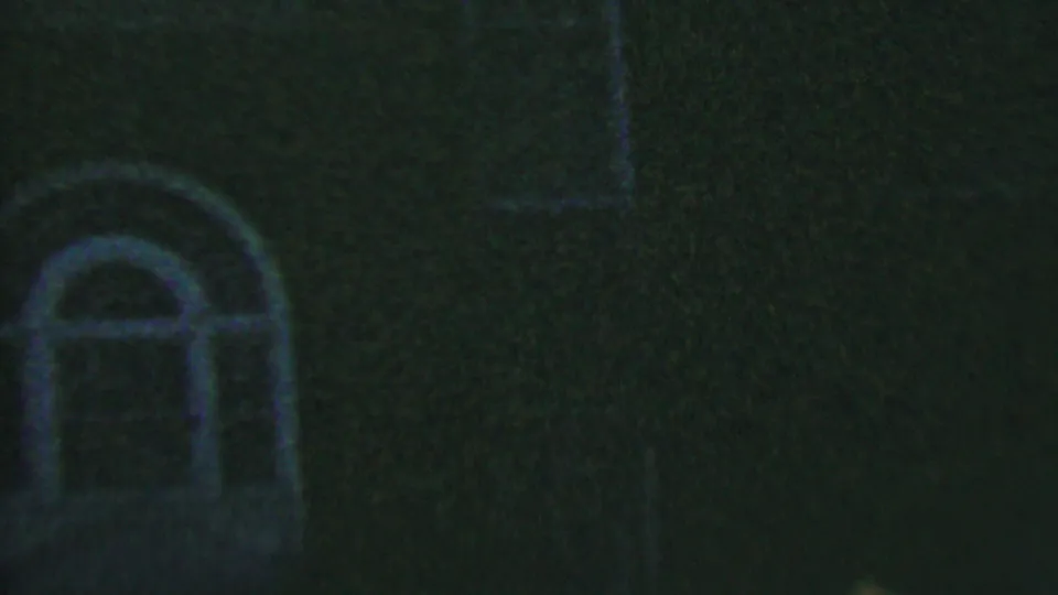 Low-light Hatfield, Pennsylvania frame showing arched window shapes and brickwork on a building exterior in grainy 8mm footage from 1956.