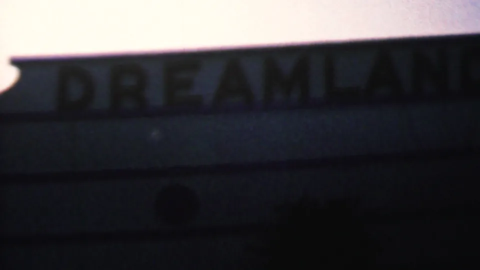 Soft, handheld view of the partial Dreamland sign, with dark letters on a light exterior edge in 1956 Hatfield home-movie footage.