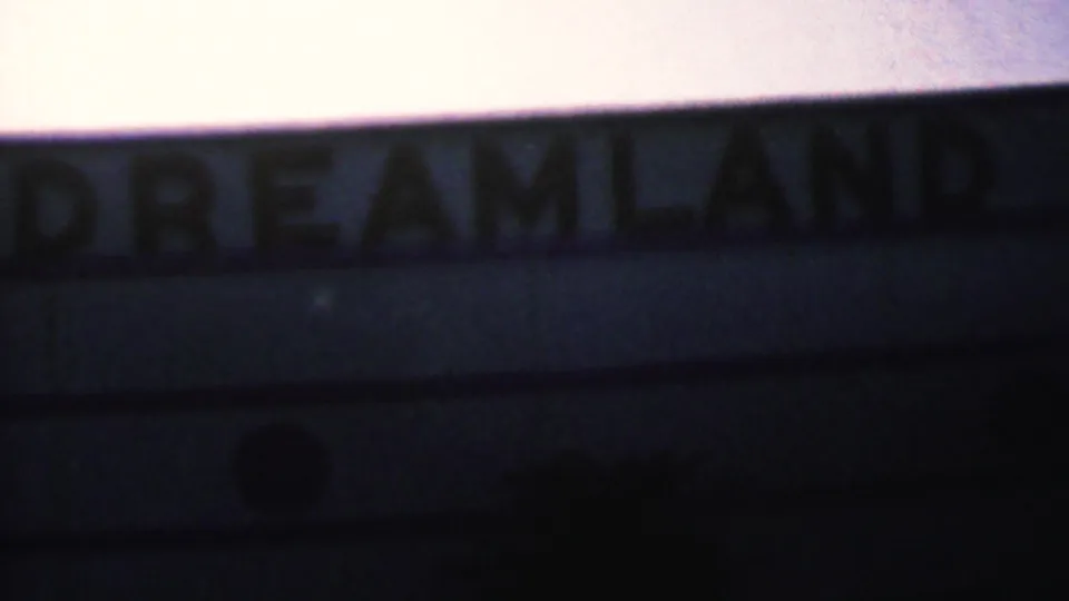 Soft-focus 1956 8mm frame from Hatfield, Pennsylvania showing large Dreamland sign lettering against a pale dusk sky and dark roofline.