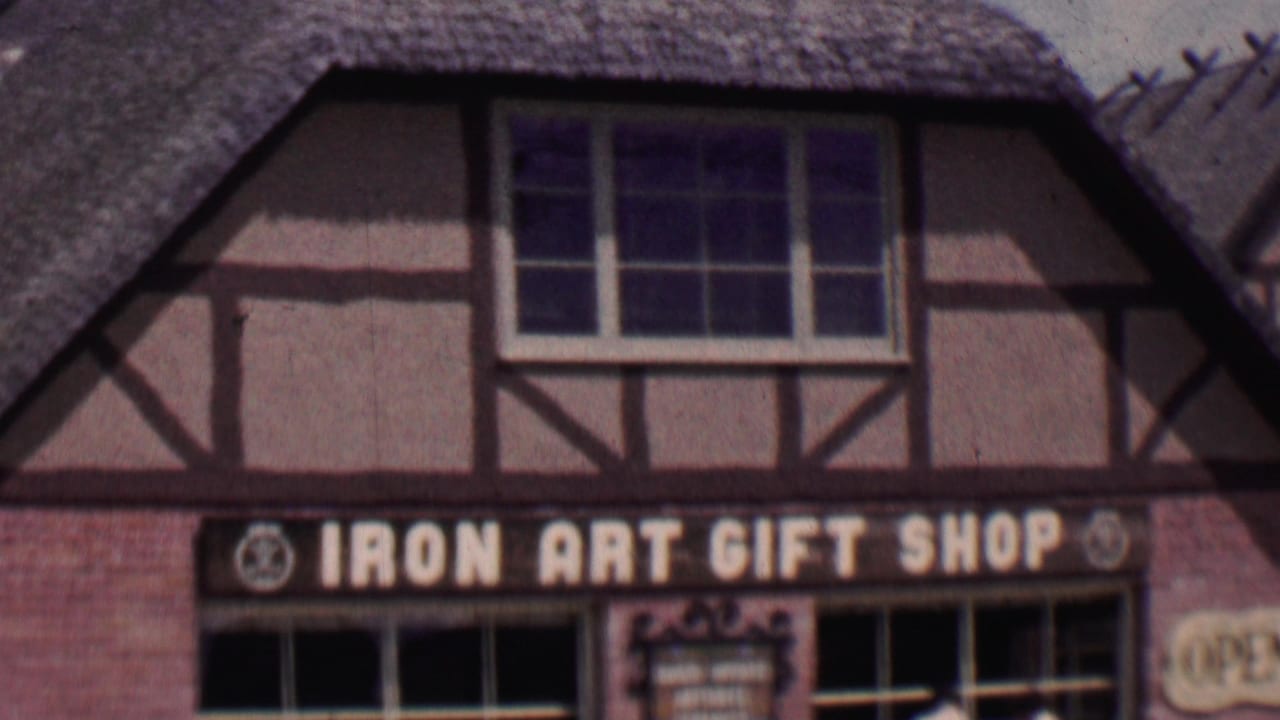 Solvang, California storefront view from 1955 showing the Iron Art Gift Shop sign, half-timbered facade, thatched roof, and large display windows.