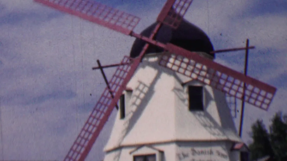 1955 Solvang frame showing the white windmill, red lattice blades, dark cap, small windows, and partially visible lettering near the lower tower.