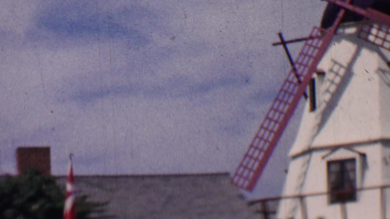 Partial view of windmills and a roofline with a Danish flag.