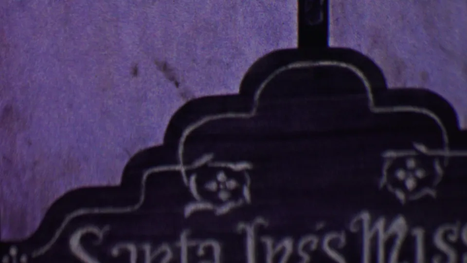 1955 Solvang frame showing the cross stem, shaped marker outline, decorative carving, and partial Santa Ines Mission lettering.