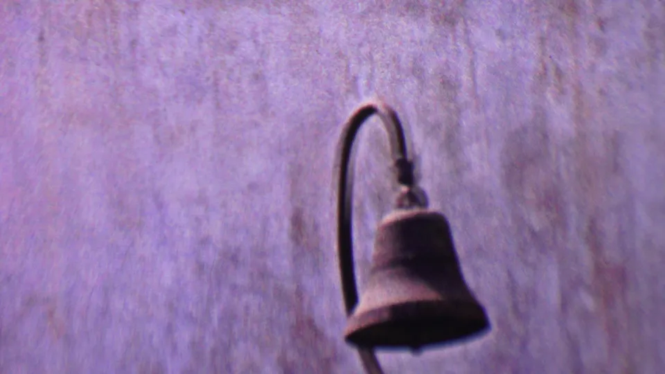 Textured mission wall in the Solvang footage with a dark curved lamp fixture hanging against the plaster surface.