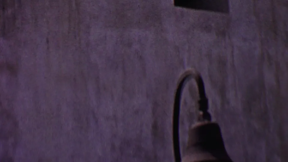 Later frame showing a similar textured wall and curved hanging lamp, likely within the Santa Ines Mission visitor area shown in the clip.