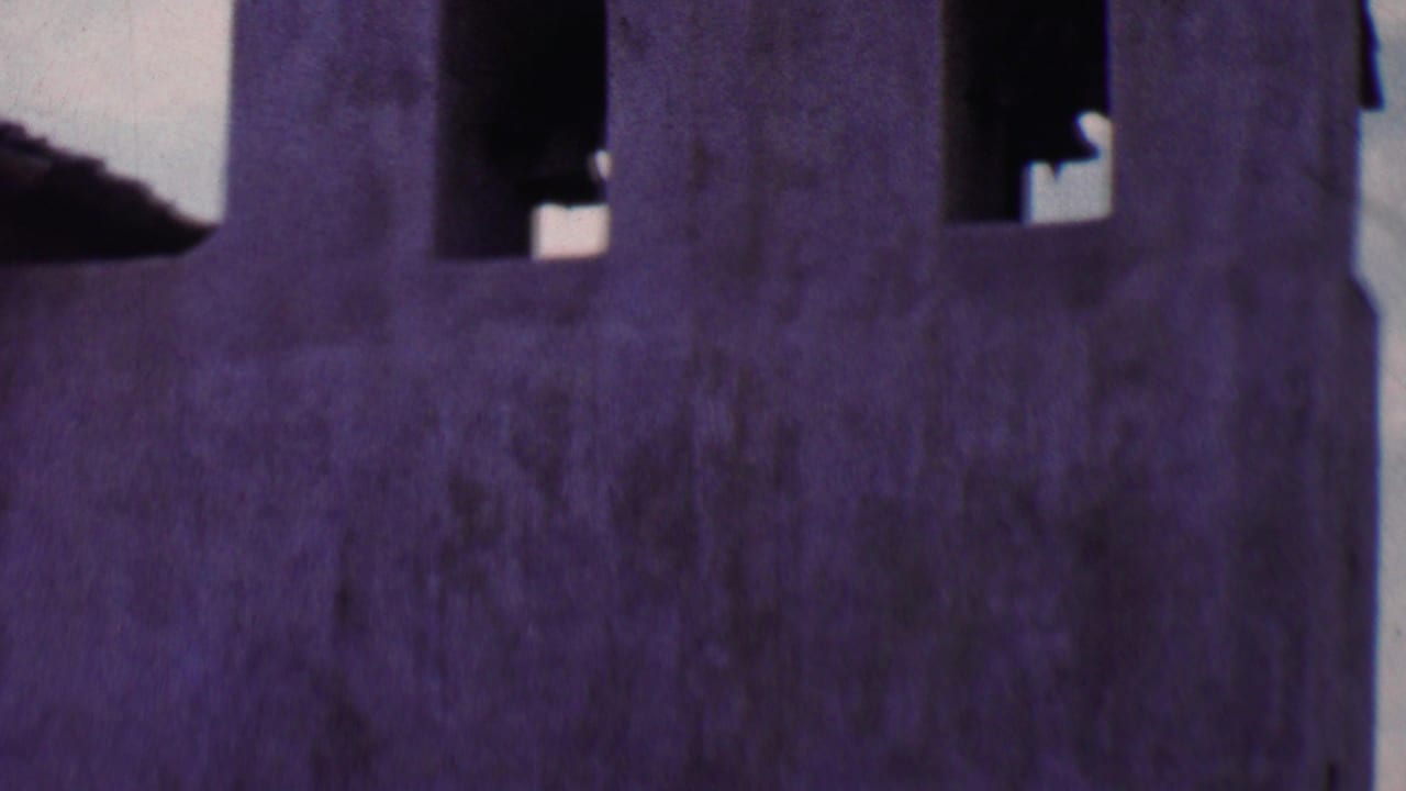 Cropped section of stucco wall with bell openings near the roofline.