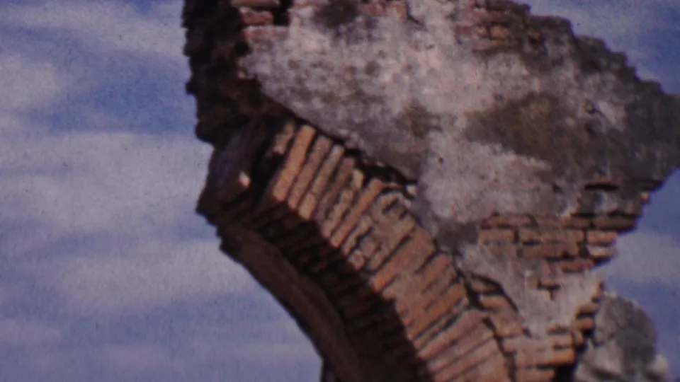 1955 Solvang 8mm frame showing a close view of broken brickwork and weathered stucco on a church or mission-style ruin against blue sky.