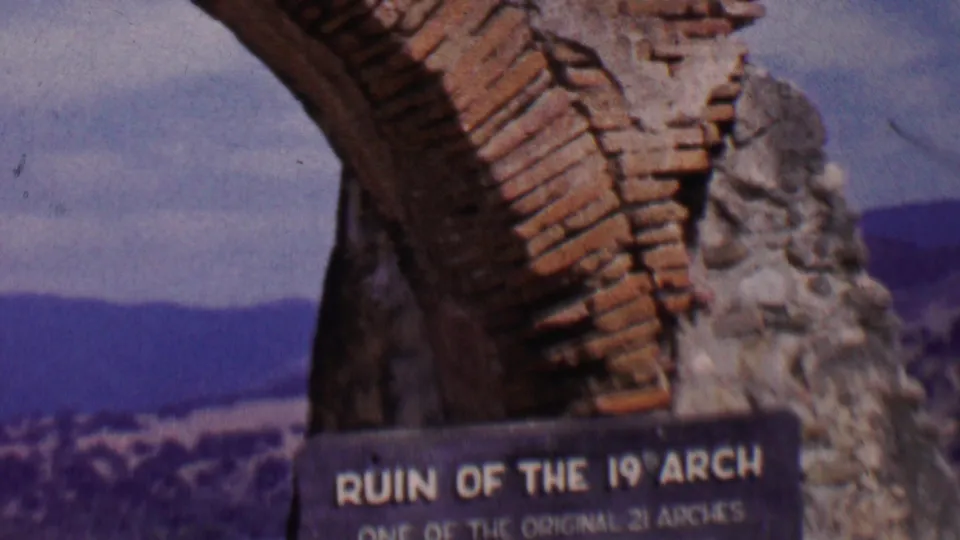 1955 Solvang 8mm frame showing the mission arch remnant with the identifying plaque beginning to enter the lower edge of the shot.