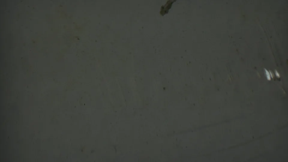 Metadata-supported 1950 Detroit 8mm frame showing an abstract textured surface with a dark blemish, dust specks, scratches, grain, and small bright streaks.
