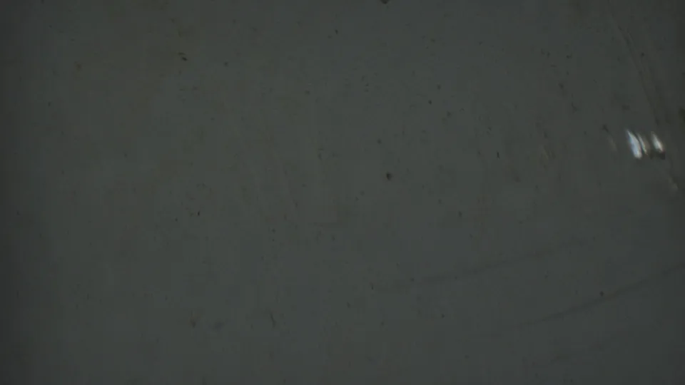 Metadata-supported 1950 Detroit 8mm frame showing a grainy gray-green surface with scattered dust, faint scratches, small bright marks, and no identifiable figures.