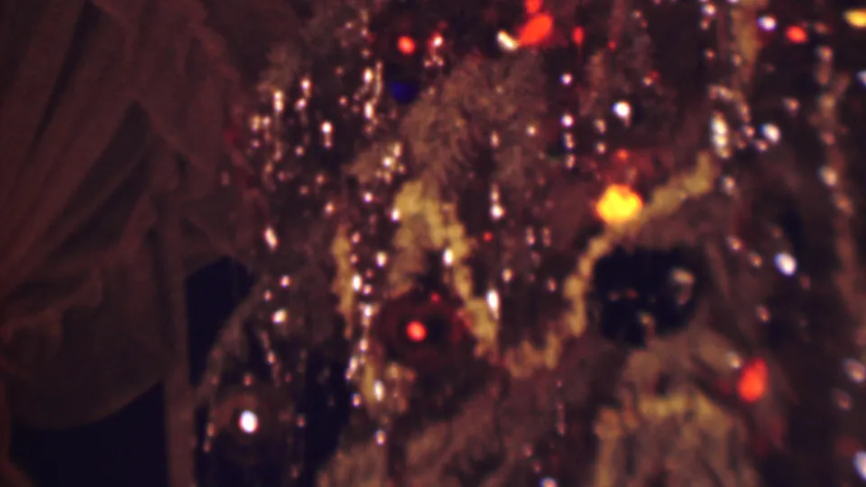 1963 Terre Haute home-movie frame ending on a close view of silver tinsel, warm colored bulbs, pale garland, and dark round ornaments on the Christmas tree.