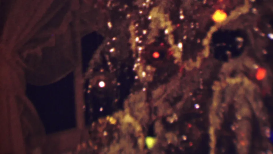 1963 Terre Haute 8mm frame showing a close, soft-focus view of a glossy brown textured object with small red, yellow, and white lights against a dark curtained interior.