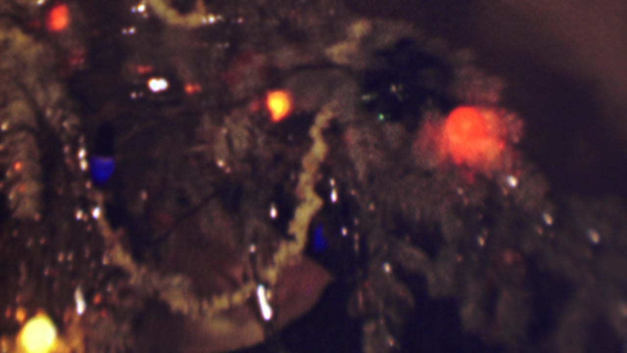 1963 Terre Haute home-movie close-up of a decorated Christmas tree with artificial snow, glowing red and blue lights, and reflective ornaments in soft focus.