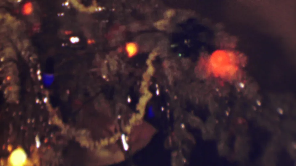 1963 Terre Haute home-movie close-up of a decorated Christmas tree with artificial snow, glowing red and blue lights, and reflective ornaments in soft focus.