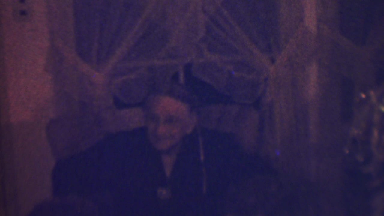At the end of the short clip, the older woman sits in shadow near holiday decorations and a Christmas tree in the private Terre Haute interior.
